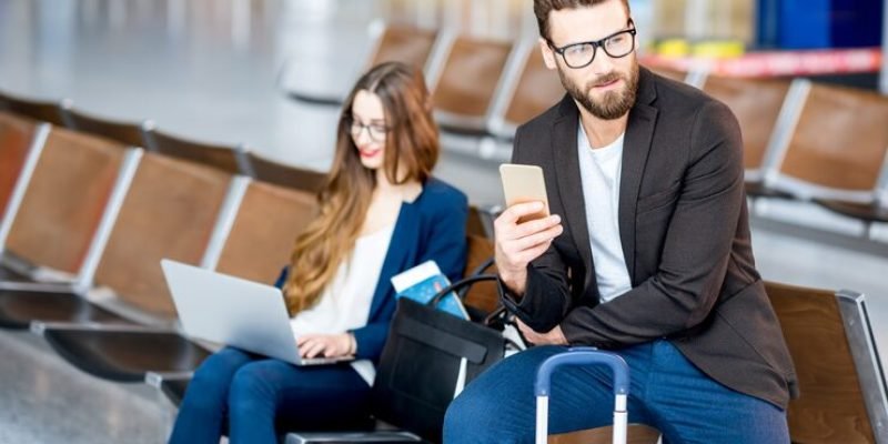 elegant-business-couple-sitting-with-laptop-phone-suitcase-waiting-hall-airport-business-travel-concept_506452-1665